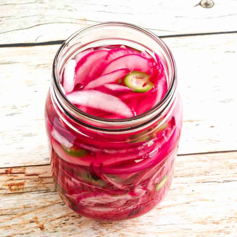 red pickled onions in a transparent container.