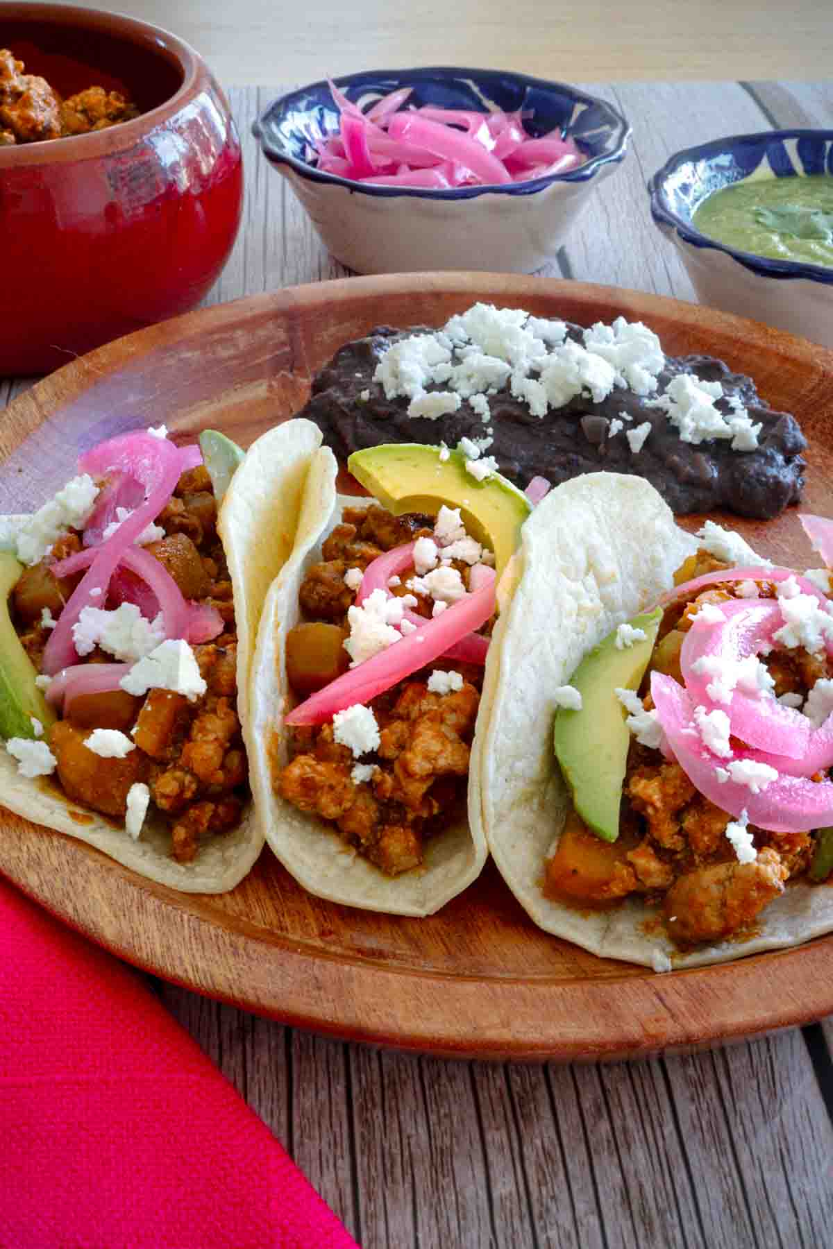 Ground pork tacos Mexican recipe - three pork tacos with red pickled onions and fried beans.
