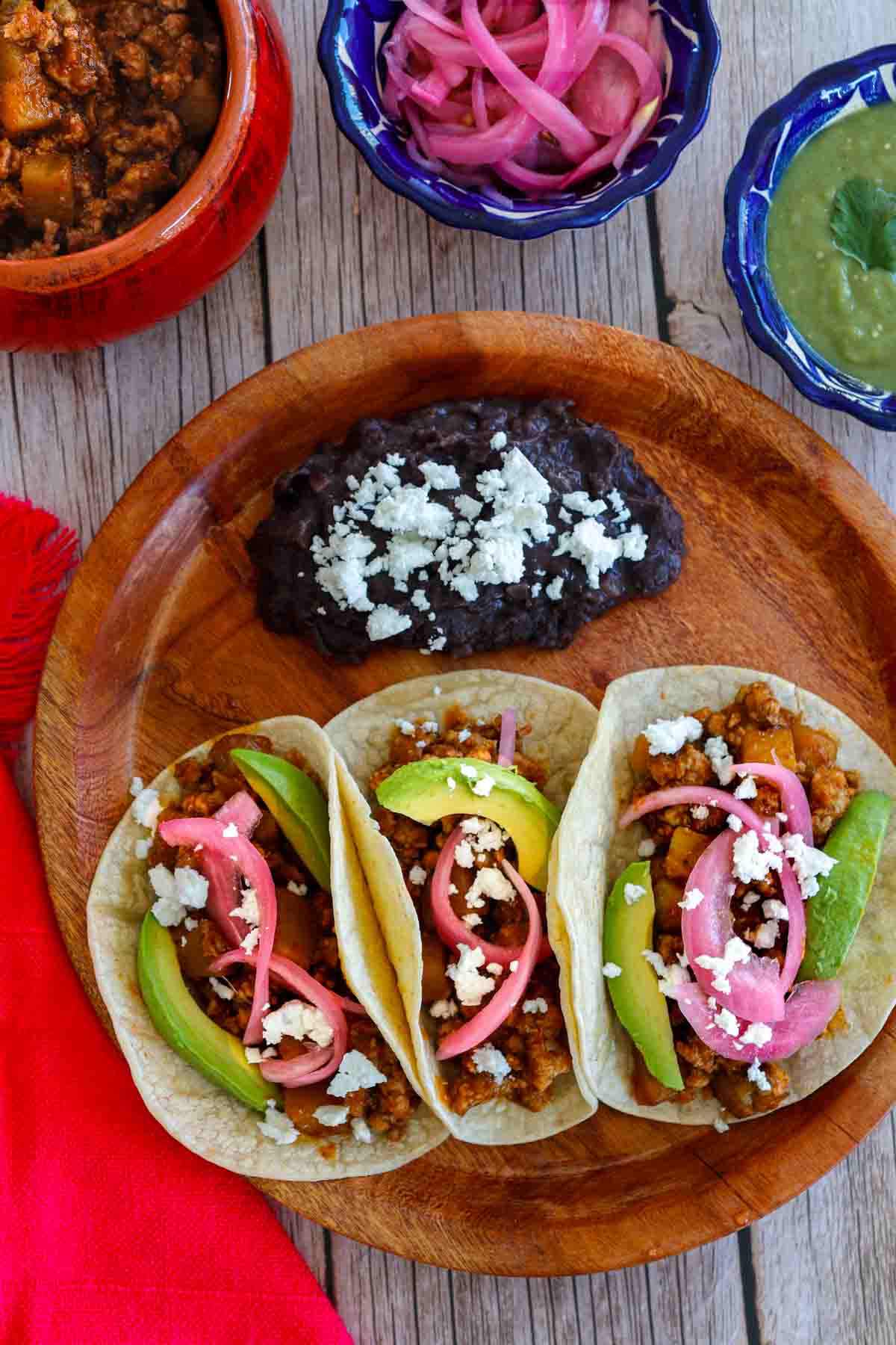 Ground Pork Tacos Three ground pork tacos with red pickled onions, avocado and salsa.