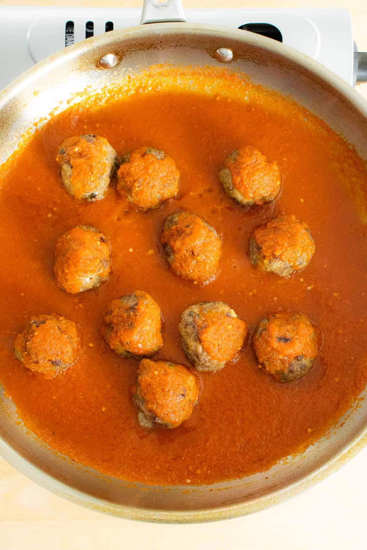 Cooked baked Mexican meatballs in pan with sauce.