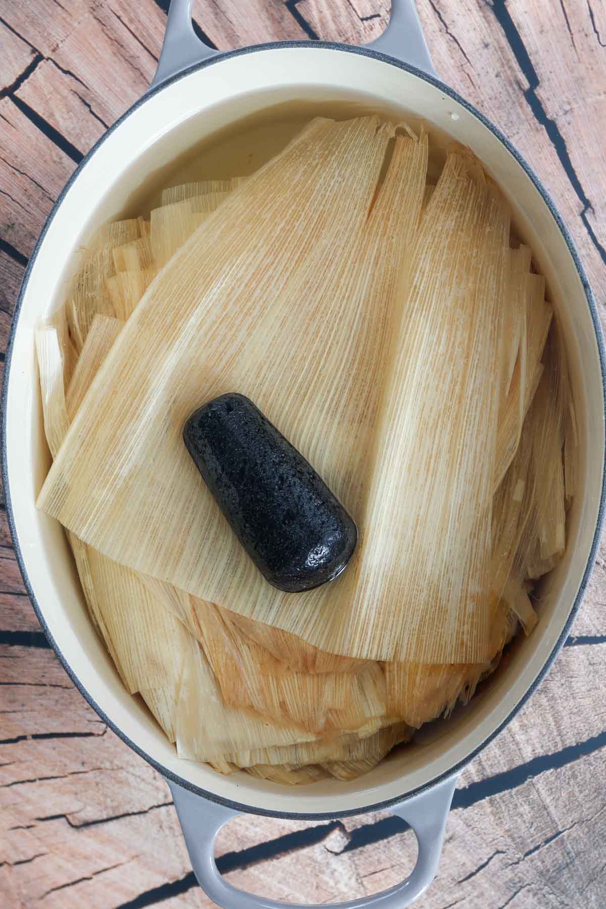 Corn husks submerged in warm water for softening.