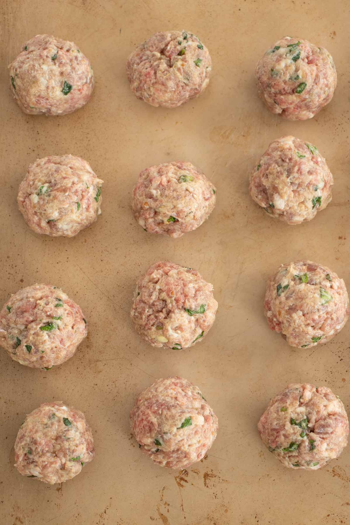 Uncooked baked meatballs in tray.