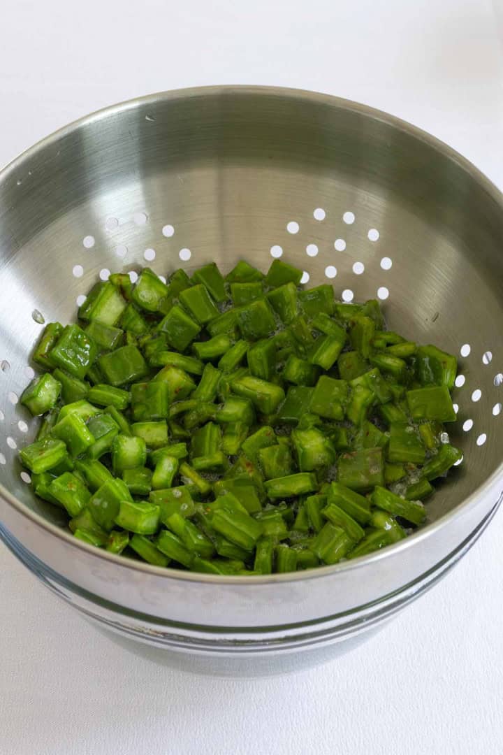 Raw nopales resting on a colander.