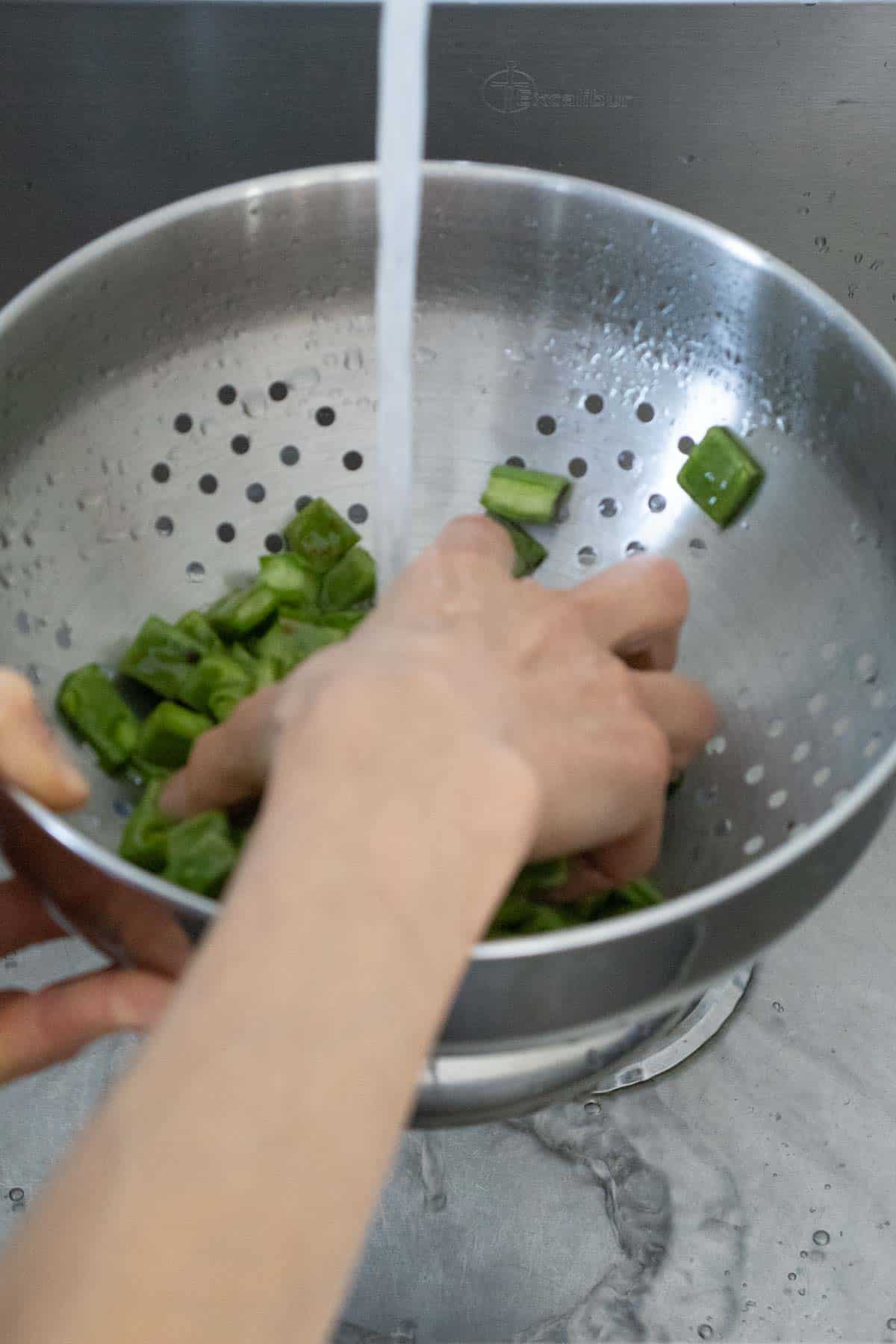 Rinsing nopales under running water.