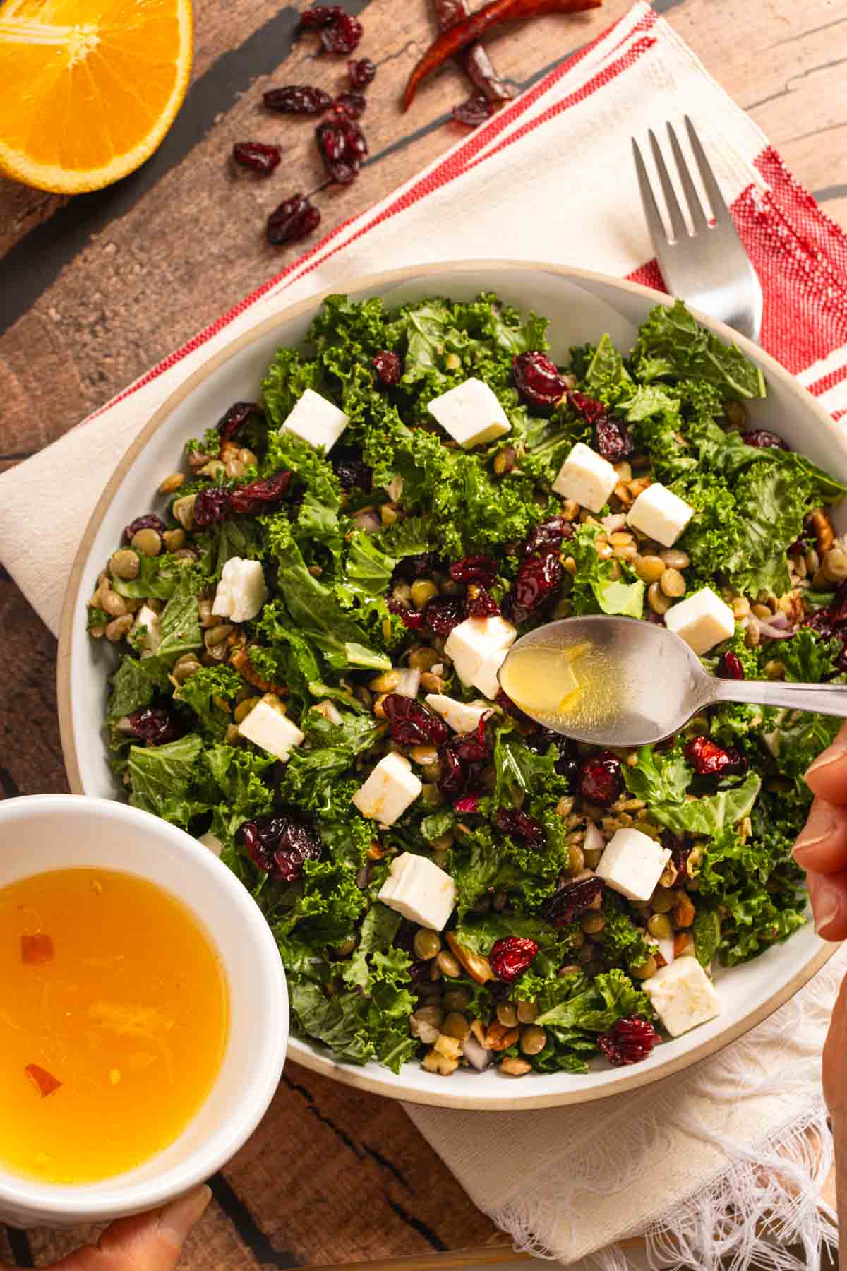 Adding the vinagrette to the Lentil and Kale salad with cranberries.