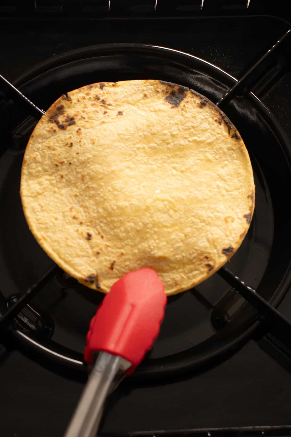 Charring the tortilla in a burner for the Red Mole sauce.