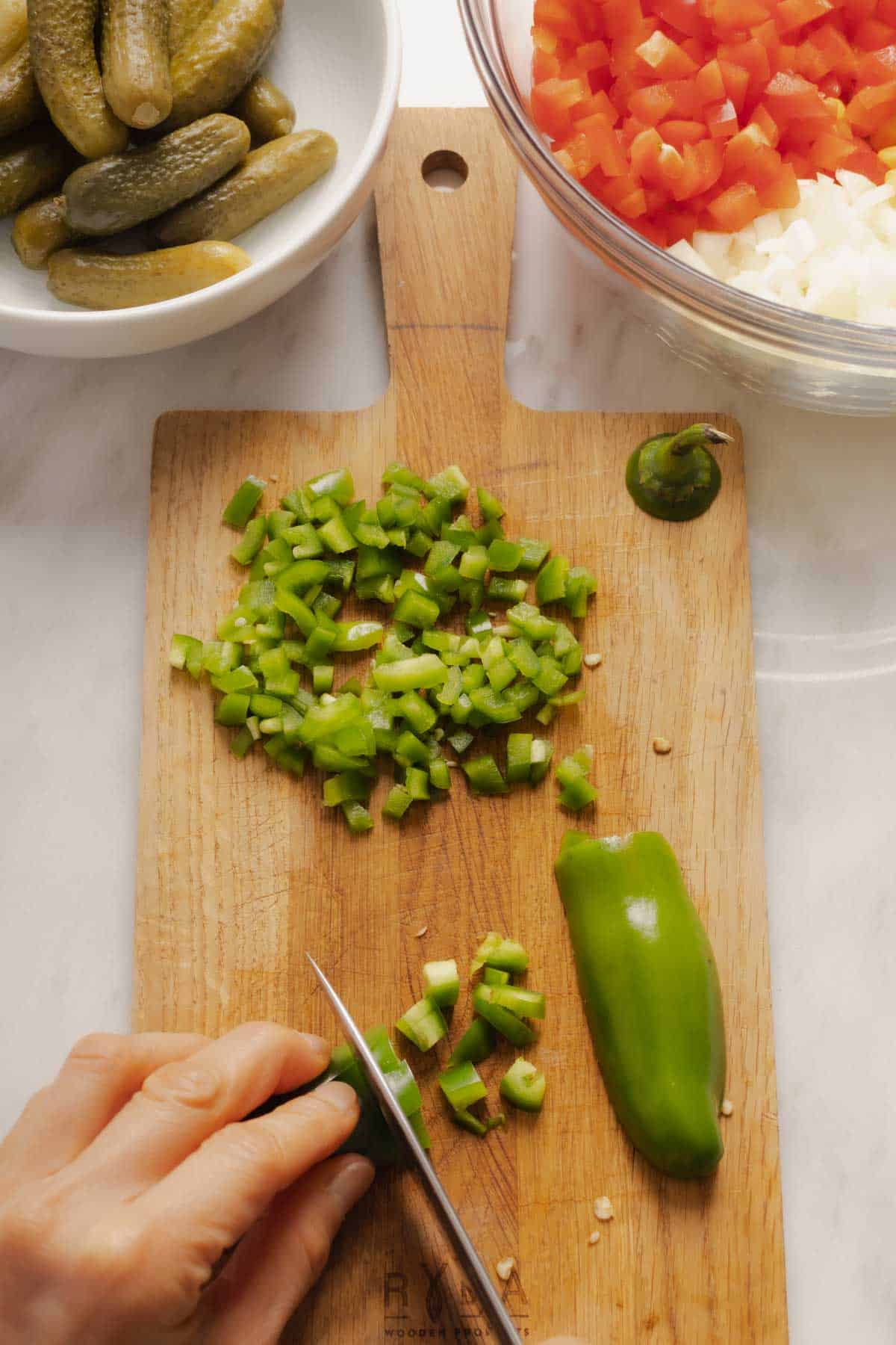 Jalapeño peppers for the pickle de gallo chopped in a wooden board.