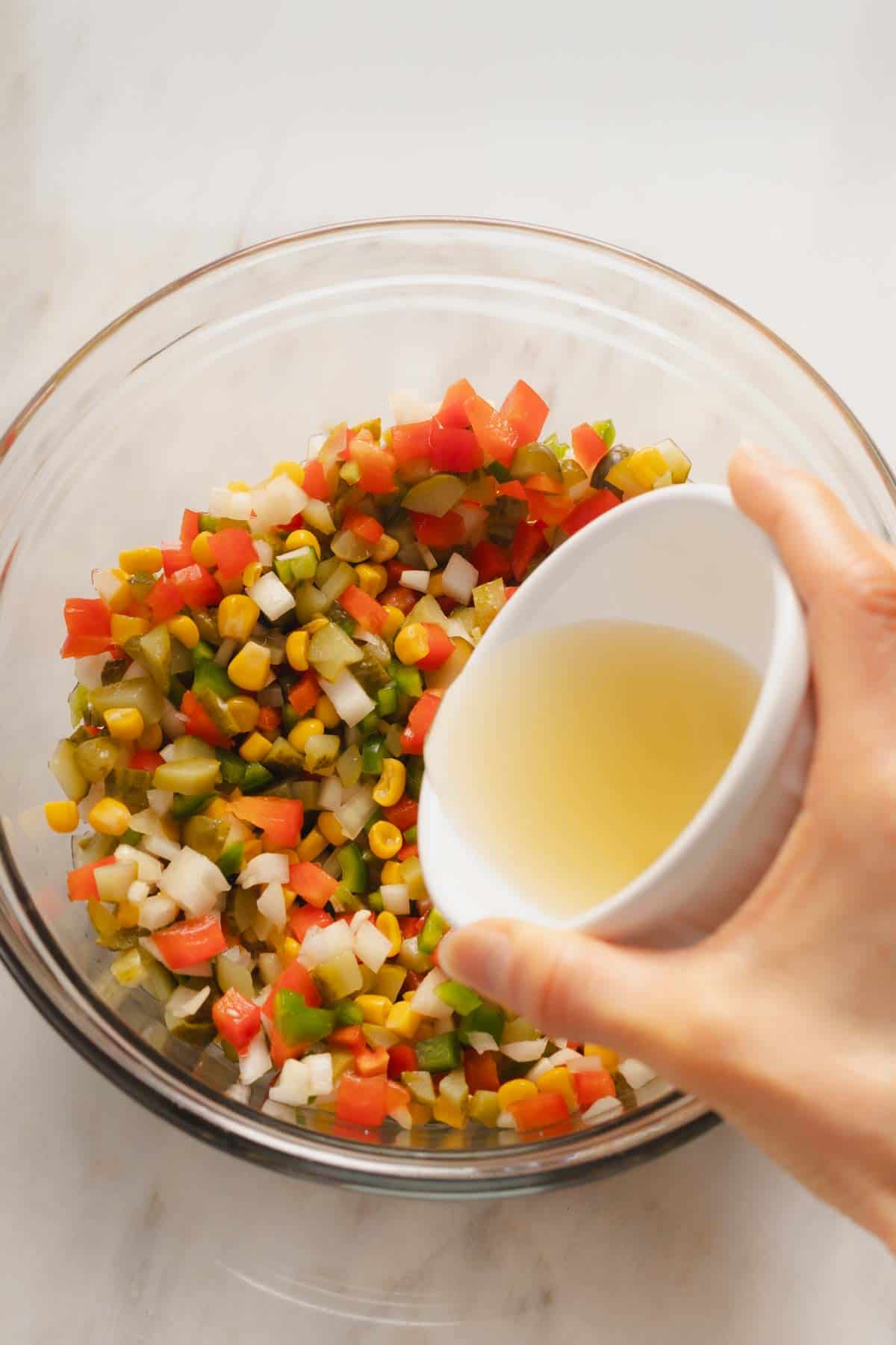 Adding the pickle brine, lime juice, and vinegar to the ingredients in the bowl.