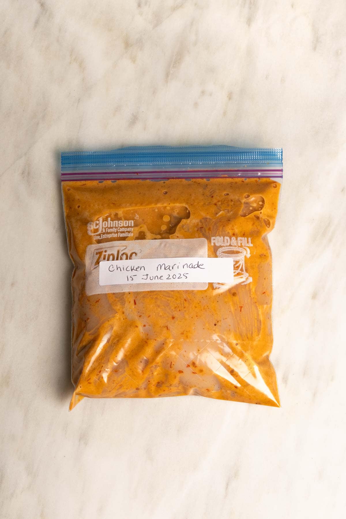 Marinated chicken resting inside zip log bag.