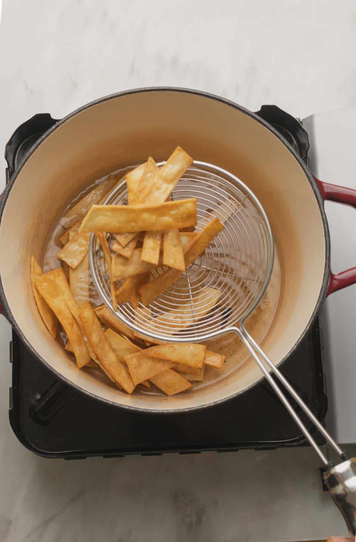 Removing tortilla strips with slotted spoon.