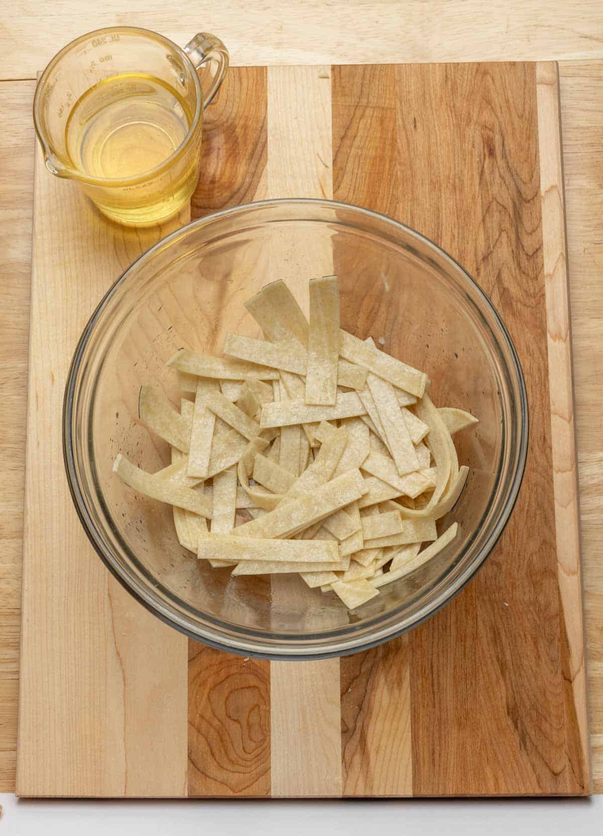 Tortilla strips tossed with oil inside bowl.