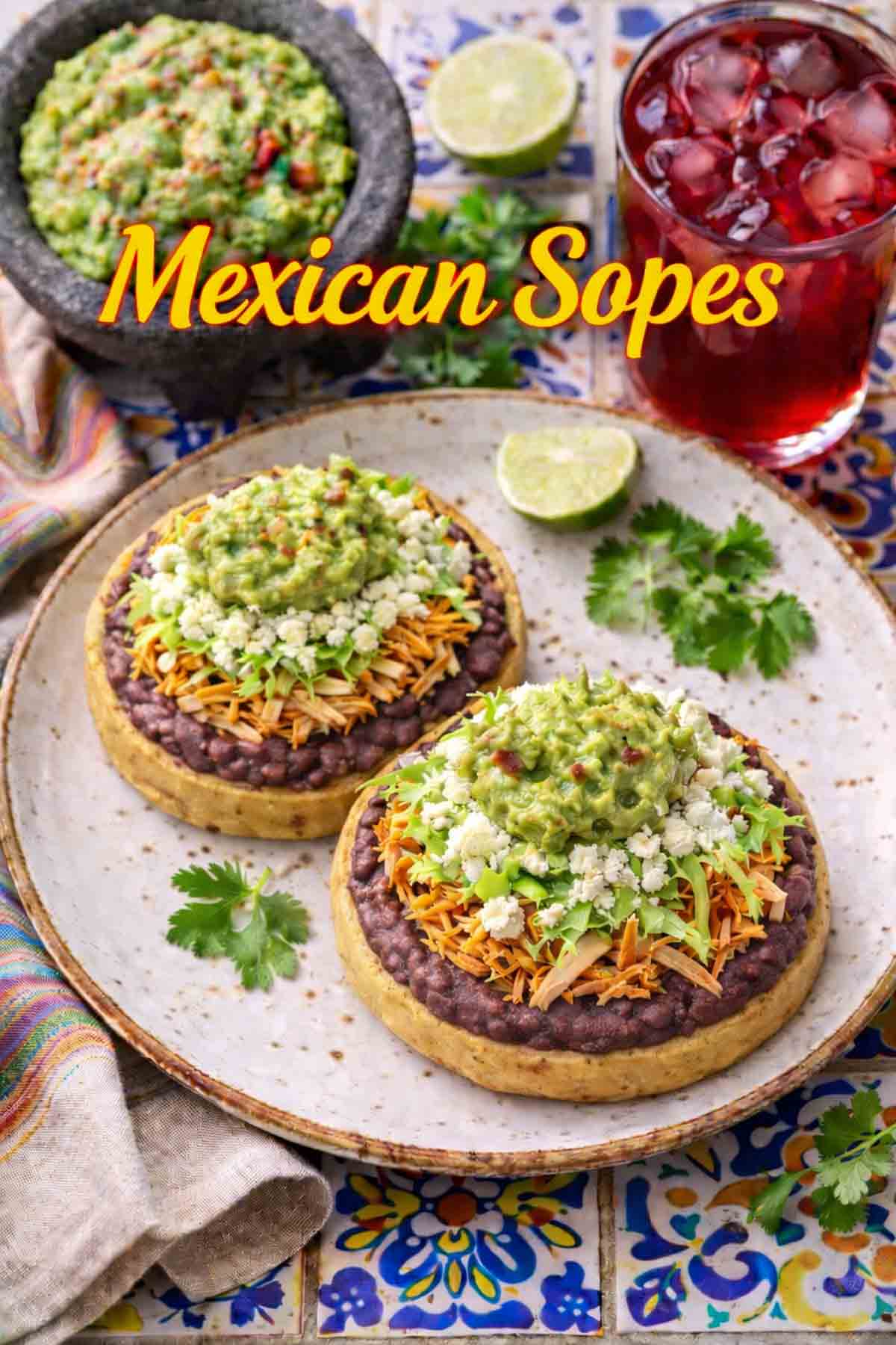Center of image, two sopes served on a plate. Top left corner is some Guacamole served in a molcajete.